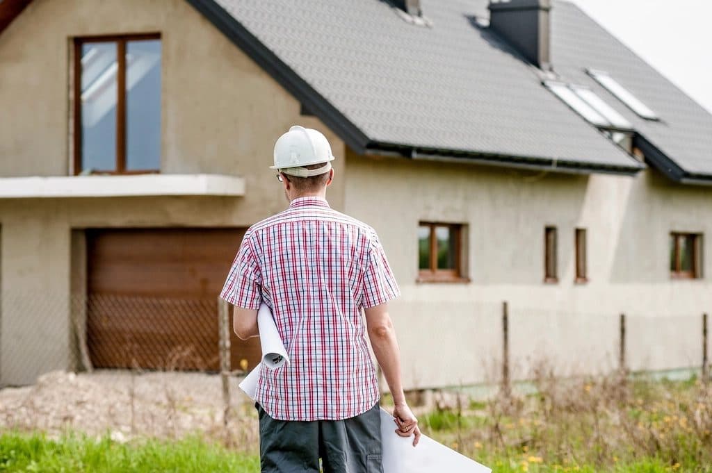 Builder with plans inspecting a new house on site